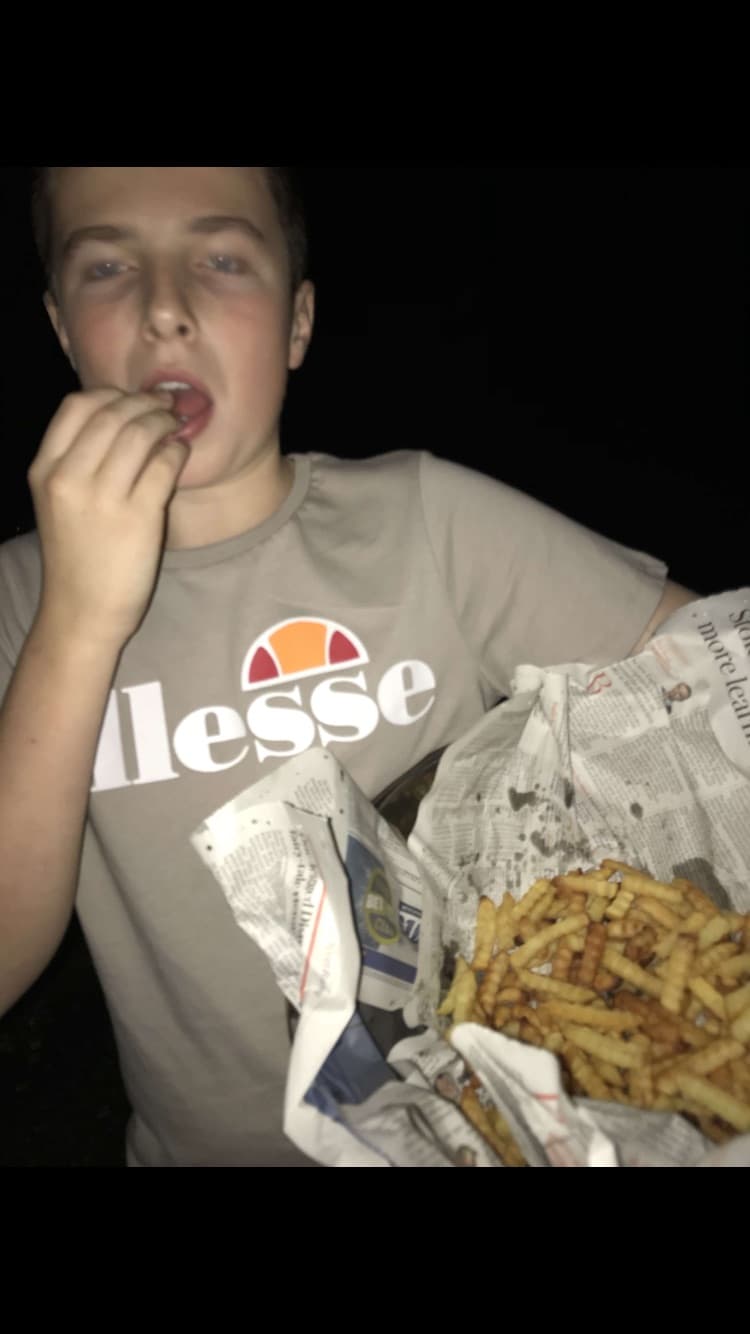 Andy tucking into a bag of chips wrapped in newspaper